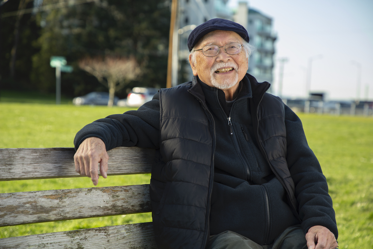 Older man on park bench smiling at camera